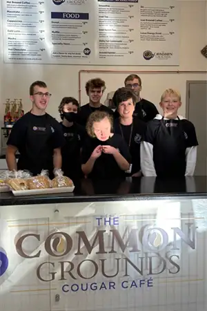 Kids standing behind a food counter for the Cougar Cafe.