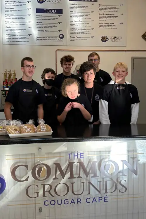 Kids standing behind a food counter for the Cougar Cafe.
